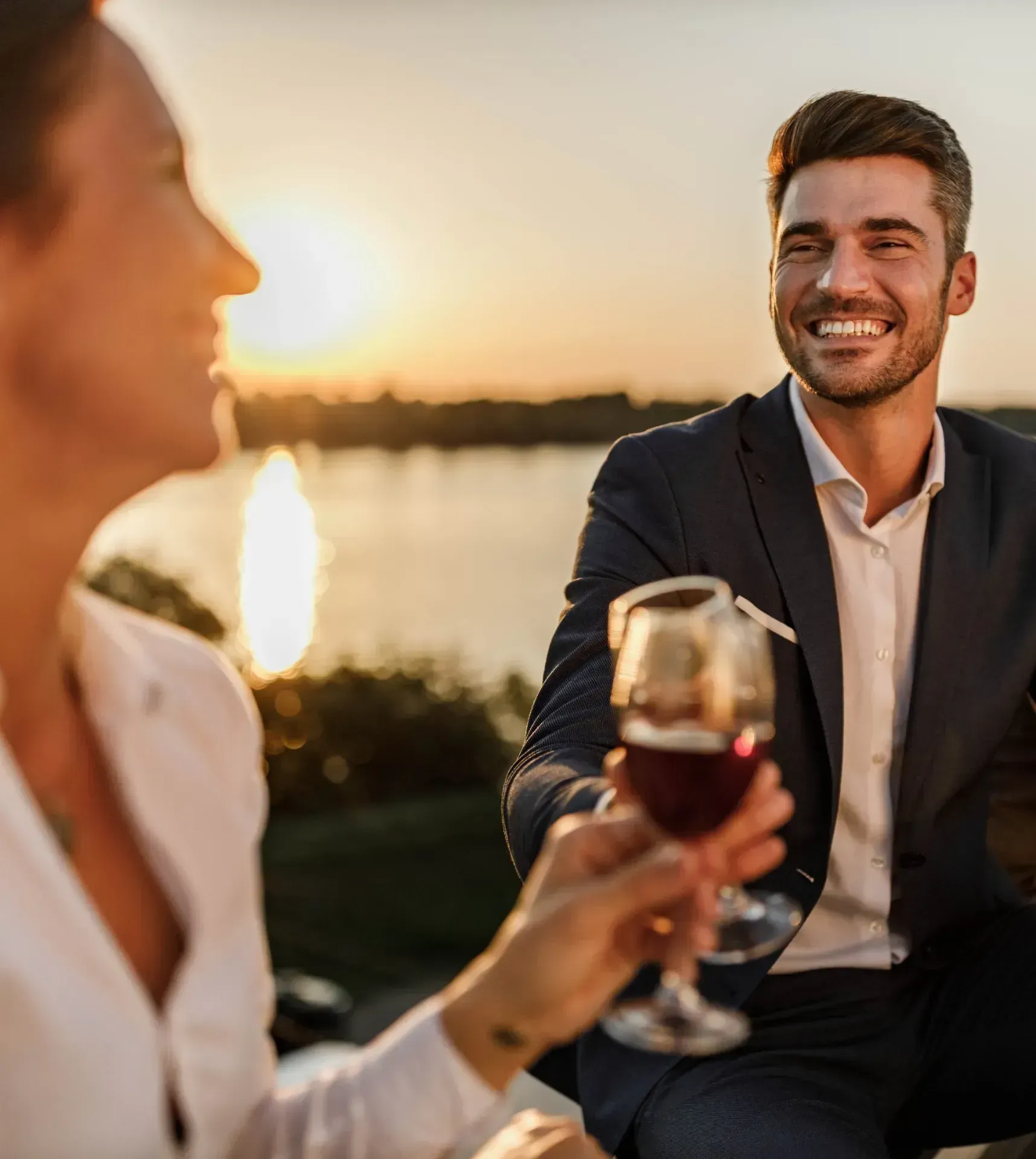 Residents enjoying drinks outdoors near the waterfront at sunset